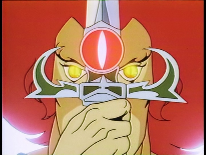 Lion-O's eyes glow with golden light as he looks through the curled crossbars of the Sword of Omens.